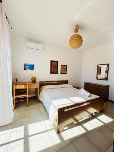 ein weißes Schlafzimmer mit einem Bett und einem Schreibtisch in der Unterkunft Villa Jolies in Viddalba