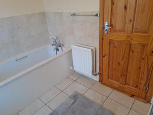 a bathroom with a white tub and a wooden door at Drogheda Townhouse in Drogheda