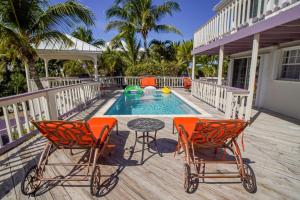 a deck with two chairs and a table next to a pool at NEW Chalk Sound Home BBQ Pool Beach Steps Away in Providenciales