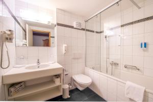 ein Bad mit einem Waschbecken, einem WC und einer Dusche in der Unterkunft Hotel Grindelwalderhof in Grindelwald