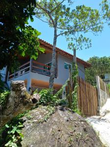 a house from the outside with a tree at Mar Doce Lar Suítes Trindade in Trindade