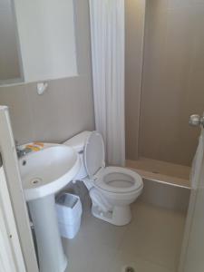 a white bathroom with a toilet and a sink at HOTEL PARAACO in Paracas