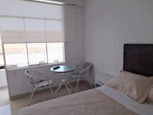 a bedroom with a bed and two chairs and a table at HOTEL PARAACO in Paracas