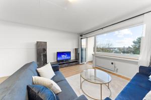 un salon avec un canapé bleu et une télévision dans l'établissement VINFUL: Premium-Apartment mit Balkon und Parkplatz, à Mülheim