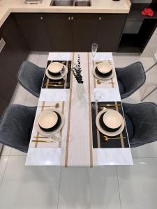 a dining room table with chairs and a table set with plates at Wind Serenity & FOC Netflix Access Country Garden Danga Bay 3BR # 6-11 pax by Minshuku in Johor Bahru