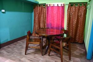 a dining room with a wooden table and chairs at Kajal's Home stay in Siliguri