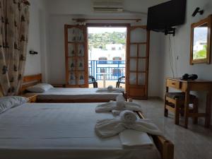 a hotel room with three beds and a window at George Studios Stalida in Stalís