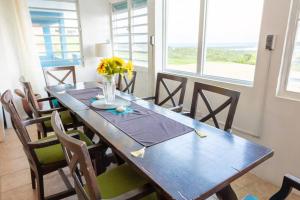 una mesa de madera con sillas y un jarrón de flores. en Hill Top Apartment with 360 Degree Balcony View, en Vieques