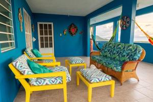 una sala de estar con paredes azules y sillas amarillas. en Hill Top Apartment with 360 Degree Balcony View, en Vieques