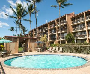 a swimming pool in front of a hotel with palm trees at Maui Vista 3406 - Ocean View Penthouse Sleeps 7 in Kihei