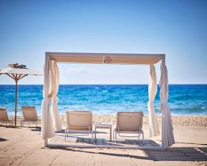 a wedding ceremony set up on the beach at Baia Di Chia Resort Sardinia, Curio Collection By Hilton in Chia