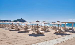 a row of chairs and umbrellas on a beach at Baia Di Chia Resort Sardinia, Curio Collection By Hilton in Chia