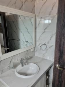 Baño blanco con lavabo y espejo en SUITES GARZOTA en Guayaquil
