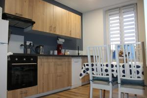 cocina con armarios de madera, mesa y 2 sillas en Appartement Royale, en Rocroi