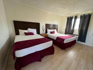ein Hotelzimmer mit 2 Betten mit roter Bettwäsche in der Unterkunft Hometown Inn North Hills in North Hills