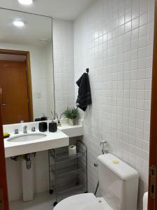 uma casa de banho com um WC, um lavatório e um espelho. em Apartamento Boutique Barra da Tijuca Península no Rio de Janeiro
