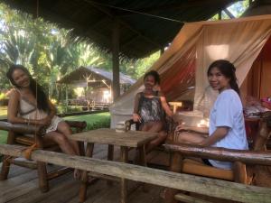 drie meisjes zitten op een tafel in een tent bij Pandora Glamping in Quezon