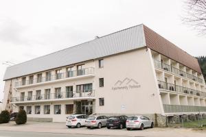 duży biały budynek z zaparkowanymi przed nim samochodami w obiekcie Parkowe Szczyrk w Szczyrku