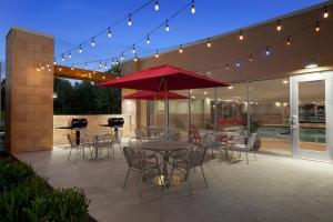 a patio with tables and chairs and a red umbrella at Home2 Suites By Hilton East Haven New Haven in East Haven