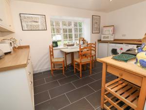 een keuken met een tafel en stoelen en een keuken met een fornuis bij The Cottage in Holywell