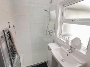 Un baño blanco con lavabo y ducha. en Teulu, en Llangollen 17 fotos más