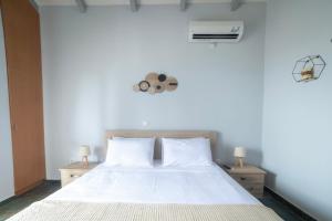 a bedroom with a white bed with two night stands at Green Garden in Porto Heli