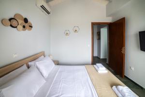 a bedroom with a bed with white sheets and a television at Green Garden in Porto Heli