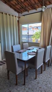 uma sala de jantar com mesa e cadeiras e uma janela em casa suite cabo frio em Cabo Frio mais 8 fotografias