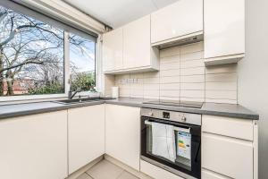 a white kitchen with a sink and a stove at Pass the Keys Whitechapel Central Apartment in London