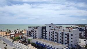 - un grand bâtiment blanc sur la plage, à côté de l'océan dans l'établissement Flat em Tambaú 50m da praia, à João Pessoa