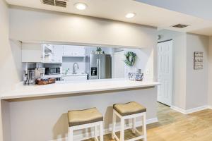 a kitchen with white cabinets and bar stools at Updated Tallahassee Townhome 3 Mi to Downtown! in Tallahassee