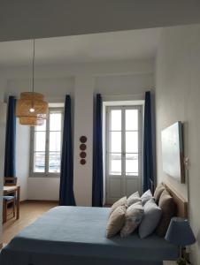 um quarto com uma cama com lençóis azuis e janelas em Aegina Port Apt 3 em Egina