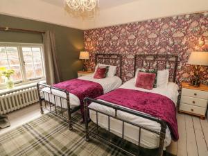 Duas camas num quarto com papel de parede floral em Liberty House em Ashbourne