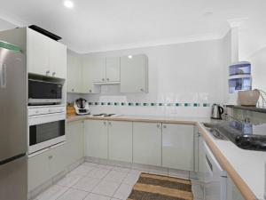 a white kitchen with white cabinets and appliances at Gold Coast best holiday resort, perfect location ! in Gold Coast