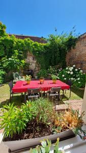 une table et des chaises rouges dans un jardin dans l'établissement Maison de charme, coeur de Douai, à Douai