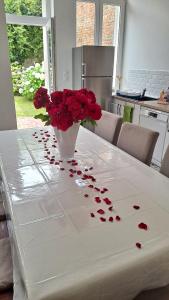uma mesa com um vaso cheio de rosas vermelhas em Maison de charme, coeur de Douai em Douai