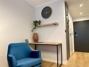 a blue chair and a desk and a clock on a wall at Eden Apartament Plac Wolności Centrum self check-in 24h in Poznań