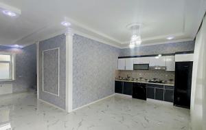 uma grande cozinha com electrodomésticos pretos e armários brancos em Qafqaz Manor Zabbix em Gabala