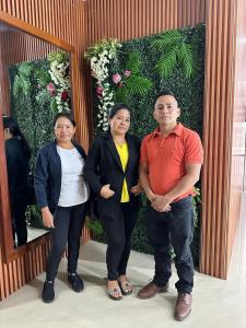 a group of three people standing in front of a wall of flowers at Hotel Villamar in Quito