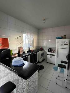 Il comprend une cuisine équipée d'un comptoir noir et d'un réfrigérateur blanc. dans l'établissement Casa de praia aconchegante, à Palhoça