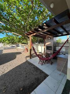 - un hamac sur une terrasse avec une table et un grill dans l'établissement Casa de praia aconchegante, à Palhoça