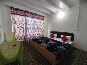 a bedroom with a bed and a green chair at Betab Valley Guest House Pahalgam in Pahalgām