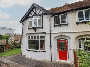 a white house with a red door and windows at Highgate in Llandudno