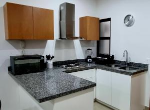 a kitchen with white cabinets and a black counter top at Confortable Departamento in Mazatlán