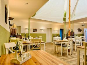 ein Restaurant mit Holztischen und weißen Stühlen in der Unterkunft Strandhaus Mönchgut Bed & Breakfast Lobbe in Lobbe