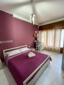 um quarto com uma cama roxa com duas toalhas em La Piazzetta Fittacamere em Torella deʼ Lombardi