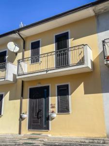 un edificio amarillo con 2 balcones y una puerta en La Piazzetta Fittacamere en Torella deʼ Lombardi