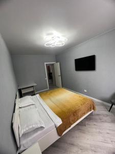 een slaapkamer met een groot bed en een flatscreen-tv bij Nureke Apartment's in Alma-Ata