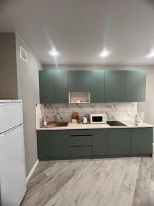 een keuken met groene kasten en een witte koelkast bij Nureke Apartment's in Alma-Ata