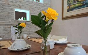 a wooden table with yellow flowers in a vase at Wild Olive Guest House & Villa in Cape Town